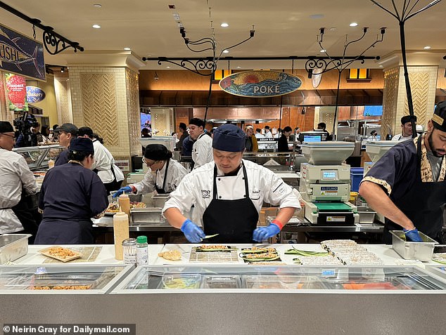 On the first floor, shoppers can purchase a variety of prepared dishes, such as sushi, sandwiches, pizza and salad.  The photo shows a chef working behind the sushi bar