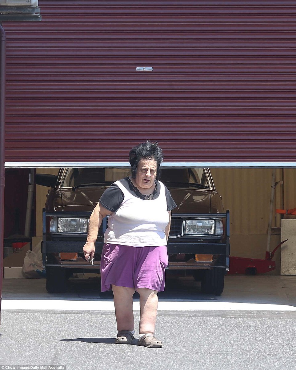 Mrs. Saikaly in front of their well-secured garage containing a modest brown sedan