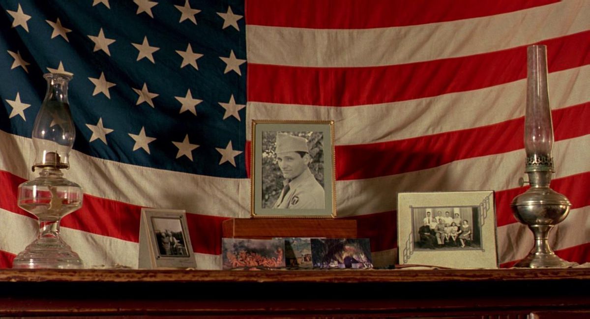 An American flag with pictures of Viggo Mortensen framed in uniform, reflected by Skin.