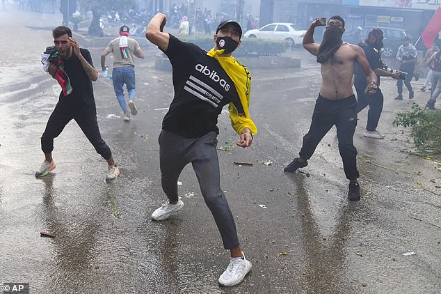 Protesters throw stones at riot police during a demonstration in solidarity with the Palestinian people in Gaza, near the US embassy