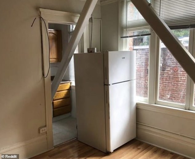 An apartment in San Francisco has a support beam in the living room doorway and a refrigerator in the doorway