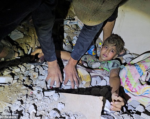 Palestinians try to rescue a boy trapped in rubble after an Israeli attack on a house in Jabalia in the northern Gaza Strip, October 19, 2023. REUTERS/Anas al-Shareef