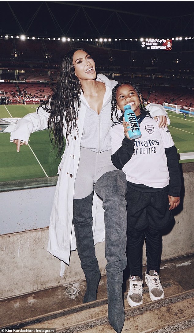 Kim and Saint pose together at the Emirates Stadium, with Saint pictured wearing Arsenal's third kit from last season with a bottle of Prime in his hand