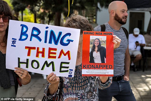 A woman holds a sign bearing the face of one of the Israeli hostages held by Palestinian militants since the October 7 attack near Tel Aviv's Azrieli Mall