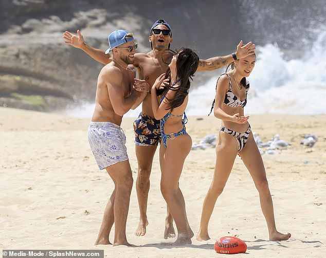 Sporty: They were seen getting a bit of exercise as they all wandered on the sunny beach