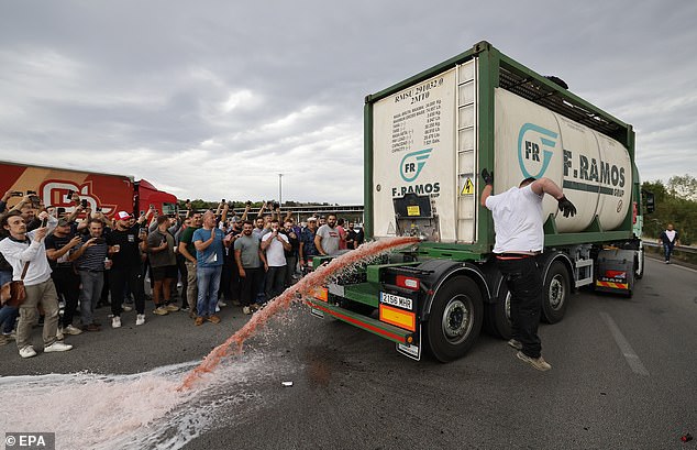 The protest, which saw the street painted red because of spilled wine (pictured above), is part of the 