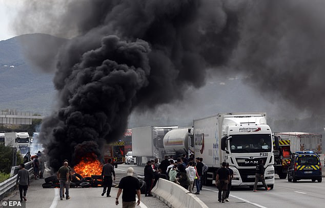 Protesters also set fire to a pile of tires, which blew black smoke into the sky (pictured) and was visible from miles away