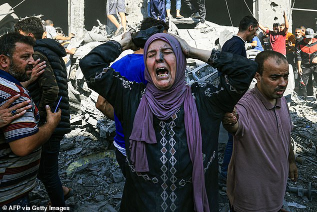 A Palestinian woman reacts as others rush to look for victims in the rubble of a building after an Israeli attack in Khan Yunis in the southern Gaza Strip on October 17