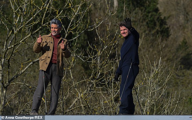 The star with Cruise waving from a train during the filming of Mission: Impossible 7 in Lewisham, North Yorkshire in 2021.