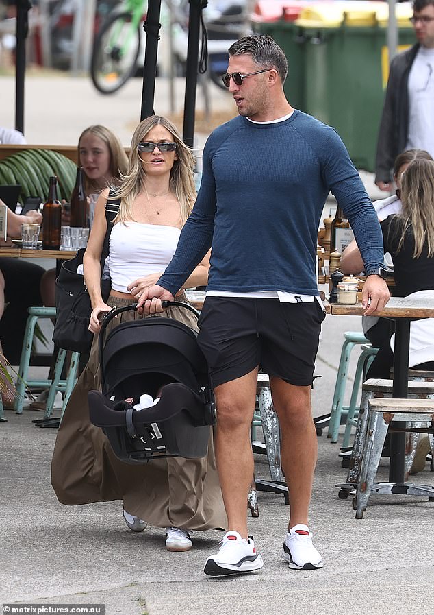 Sam, 34, wore a blue jumper, black shorts and white trainers as he carried his little girl in a black carrycot