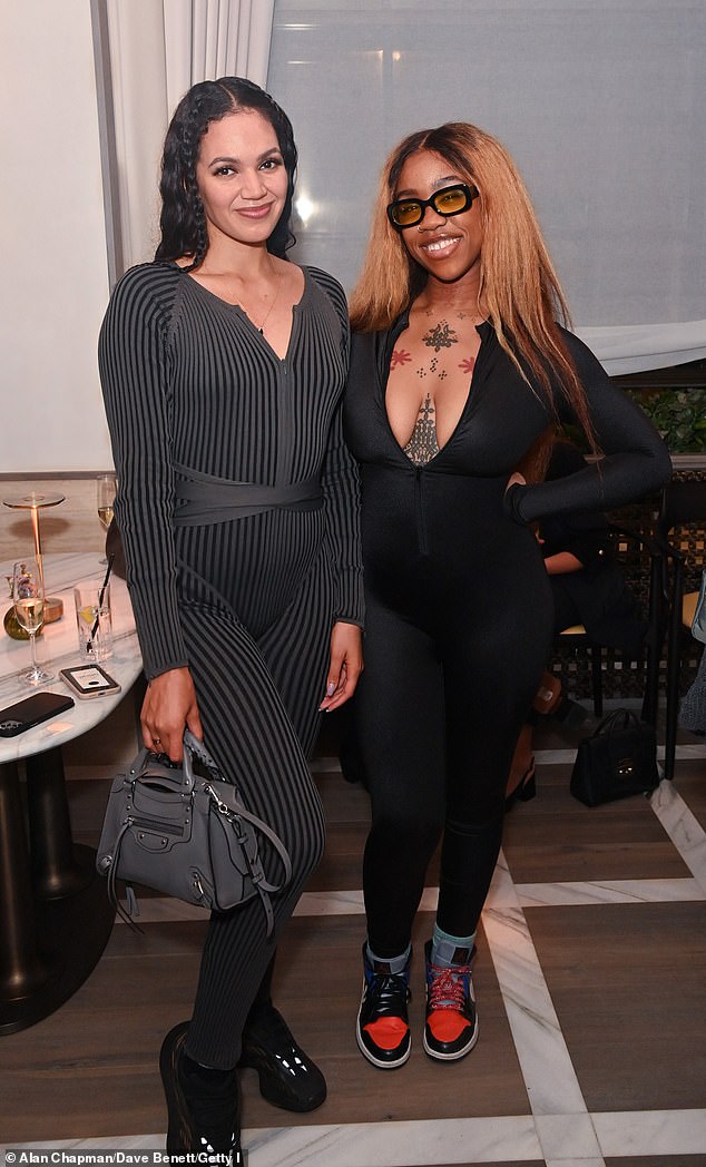 Racey: The British writer, 28, drew attention to her cleavage as the number showed off some very plunging cleavage - showing off a string of tattoos on her chest (poses with Natasha Boyce)