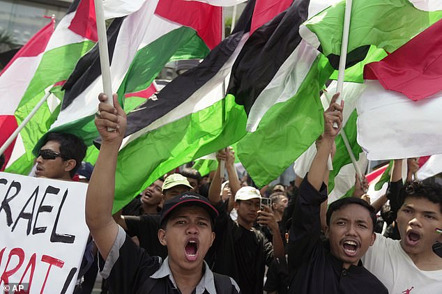 INDONESIA: Protesters shout slogans while waving Palestinian flags during a rally in support of the Palestinian people outside the building housing the UN representative office in Jakarta on Friday