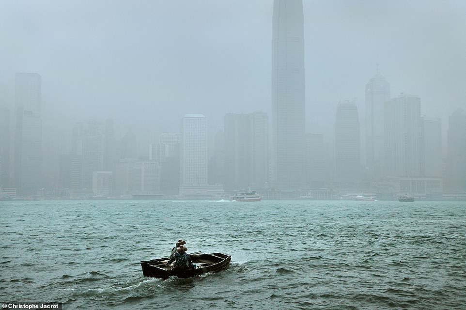 This photo shows a boat sailing through choppy waters in Hong Kong.  Jacrot writes that it was 'challenging' to find good vantage points for photographing the city in rainy weather, but that he enjoys 'working with the effects of the rain'