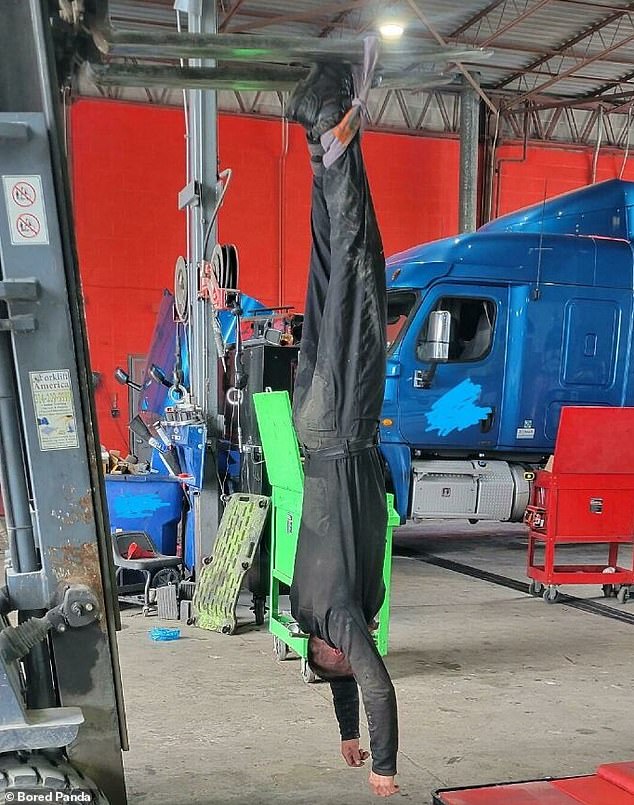 This mechanic in America appears to be hanging upside down from a piece of equipment in a car workshop - although we're not entirely sure why