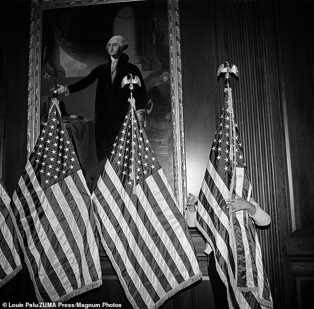 An aide to House Speaker Nancy Pelosi adjusts a row of flags in front of a painting of George Washington in the U.S. Capitol, preparing for Democratic leaders to speak after the Dec. 18, 2019, vote to elect President Donald Trump to Congress. to be turned off for the first time.