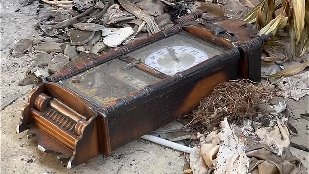 A scorched bell is depicted among the rubble of Kibbutz Nir Oz