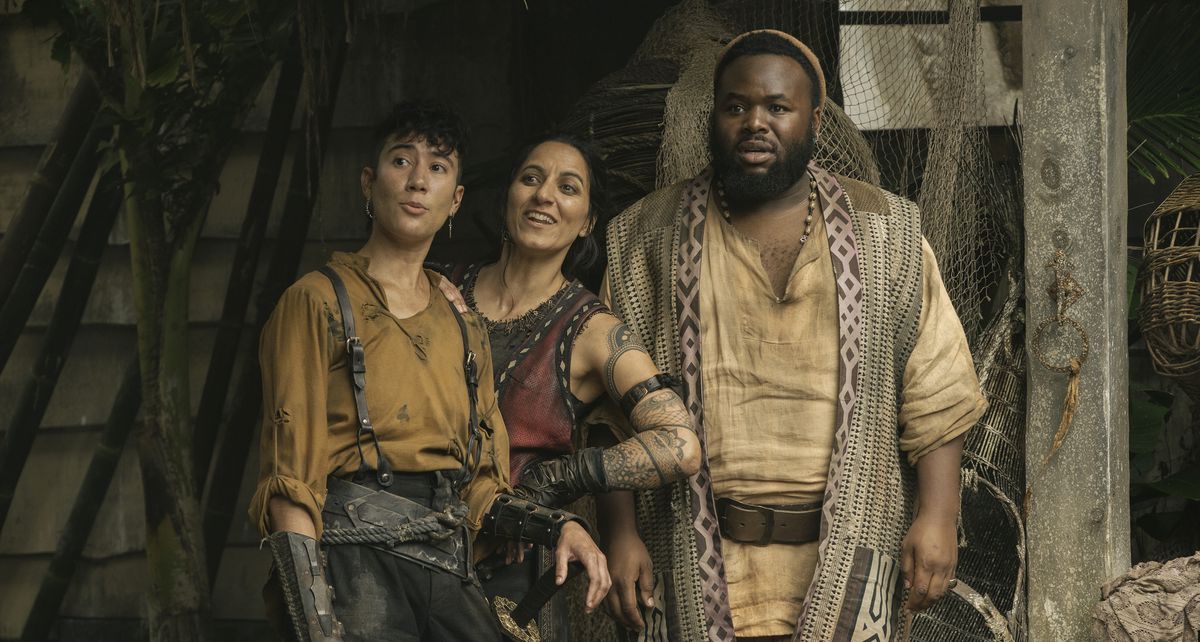 Jim (Vico Ortiz), Archie (Madeleine Sami), and Olu (Samson Kayo) are all standing outside the Pirate Republic, smiling or at something offscreen in season 2, episode 7 of our Flag Meaning Death