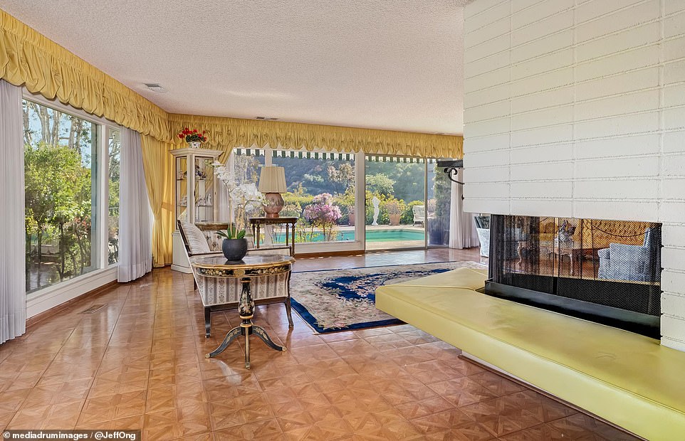 In the center of the living room is a white brick-lined fireplace, surrounded by a floating yellow hearth