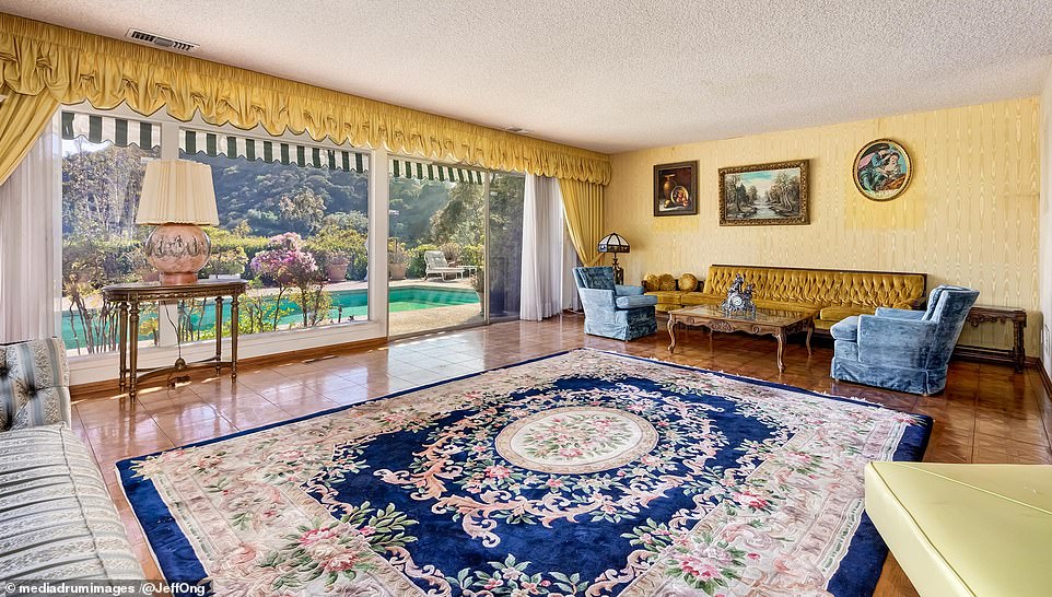 The living room features floor-to-ceiling windows and offers a view of the swimming pool in the backyard