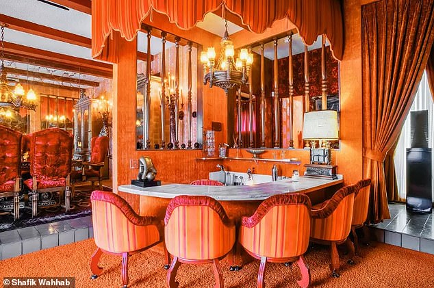 The interior is splashed with vibrant shades of orange, pink and red.  The curved wet bar (pictured) is lined with orange and pink striped chairs