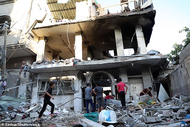 People stand among the rubble of a building destroyed by airstrikes in the town of Khan Younis in the southern Gaza Strip