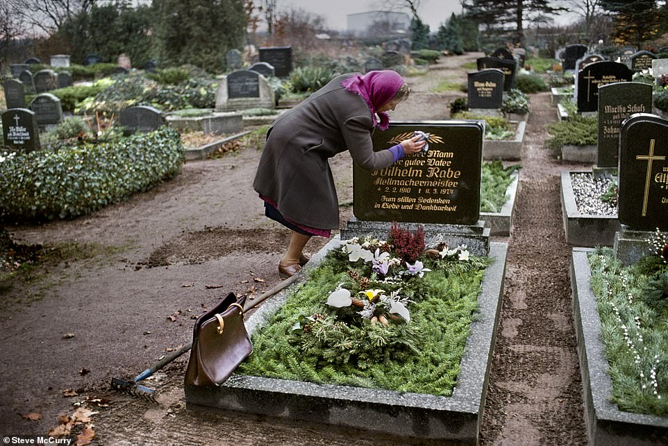 The tender moment as a woman cleans the headstone from her late husband's grave in East Germany in 1989 – the year of the fall of the Berlin Wall