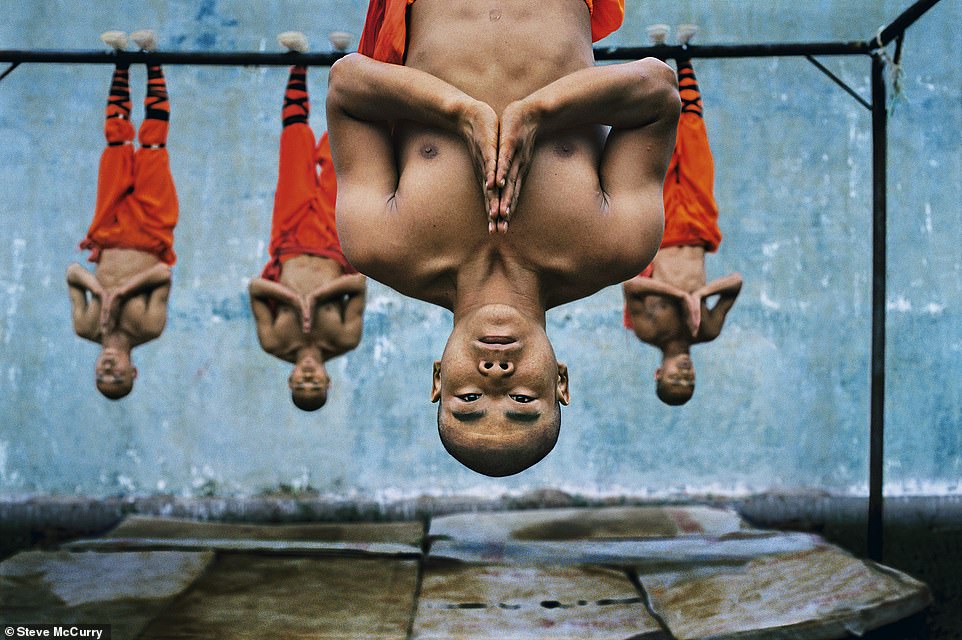 This colorful photo from 2004 shows monks hanging from a metal beam at the Shaolin Martial Arts School in Zhengzhou, China