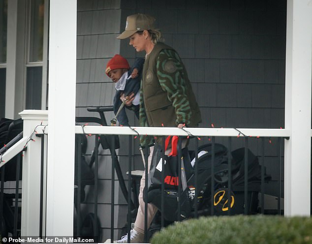 Harris walks down the stairs of the house with her son, a stroller and a bag