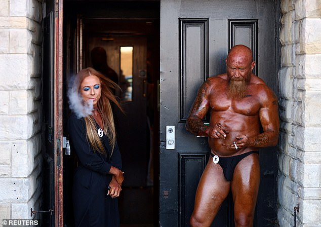 Bodybuilders Lois Moremon and Paul Chadwick enjoy a crafty cigarette and vape backstage