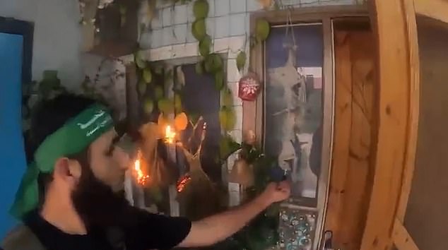 A Hamas terrorist is seen holding his lighter to houseplants and hanging ornaments in an Israeli who quickly set it on fire before they left