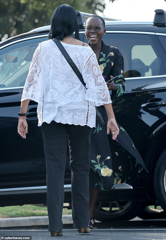 Stunning: The actress, 40, looked stunning in a long dress-like black dress with floral details, a cream coat she wore, and round-rim sunglasses