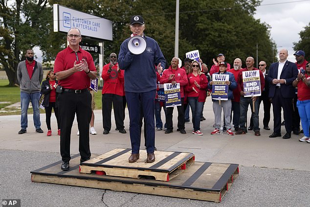 United Auto Workers President Shawn Fain, left, listens as President Joe Biden spoke to striking UAW members outside a General Motors facility last month