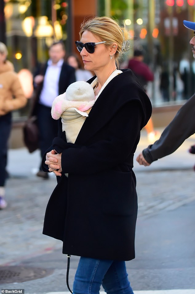 Sweet: As she walked down the street in a pair of black leather heeled boots, the 44-year-old actress held her little girl strapped to her chest under her black trench coat