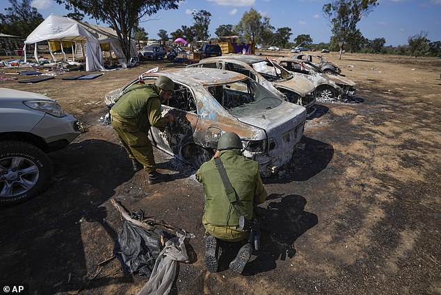 Israeli soldiers inspect the site of a music festival near the border with the Gaza Strip in southern Israel on Friday, October 13