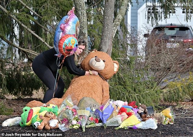 A well-wisher visits the makeshift memorial that grew in front of the family's home in Duxbury
