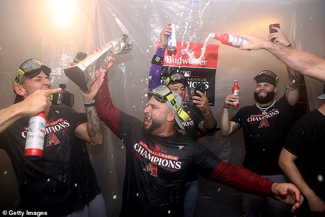 Backup catcher Jose Herrera hoists the National League trophy while being sprayed with beer