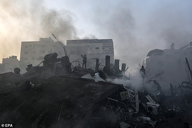 Netanyahu said the country's special war cabinet had made the final decision on when armed forces would enter the blockaded Palestinian enclave.  Pictured: Palestinians search for bodies and survivors as smoke rises from the rubble of a devastated area after Israeli airstrikes in Gaza City on Wednesday