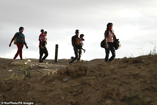 Migrants with children cross Rio Bravo from Mexico to the US on May 21, 2021 in Ciudad Juarez, Mexico