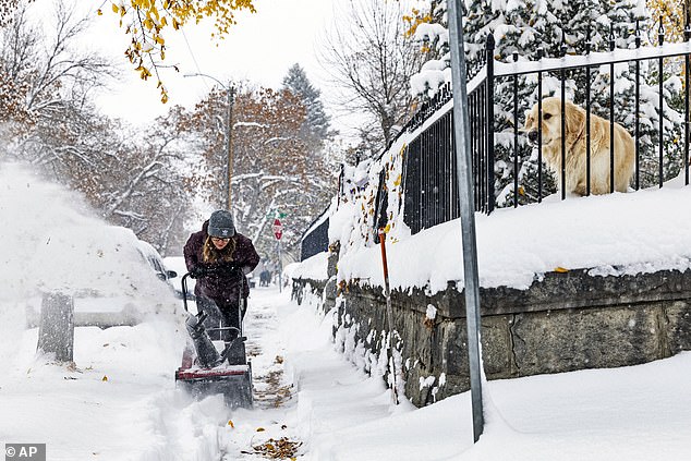 A person clears a snow-covered sidewalk in Montana.  A second wave of snow will move across the area during the night from Wednesday to Thursday