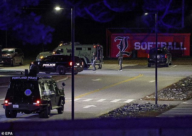 Law enforcement vehicles drive through the parking lot of the Lisbon high school gymnasium