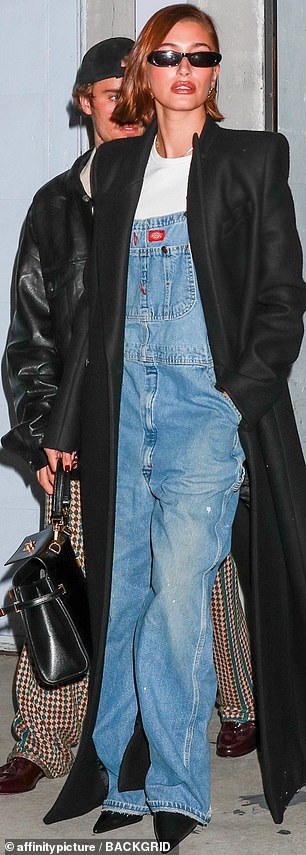 Cosy: In a concession to the plunging temperatures at the end of October, Hailey wrapped herself in a black coat that reached almost to the floor