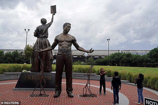 Children are seen playing near the recently unveiled Emancipation and Freedom Monument