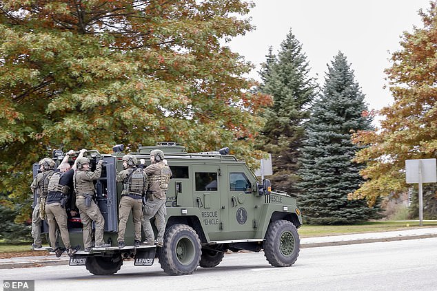 A tactical police unit makes its way through the street during the search for mass shooting suspect Robert Card