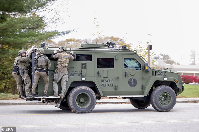 A tactical police unit makes its way through the street during the ongoing search