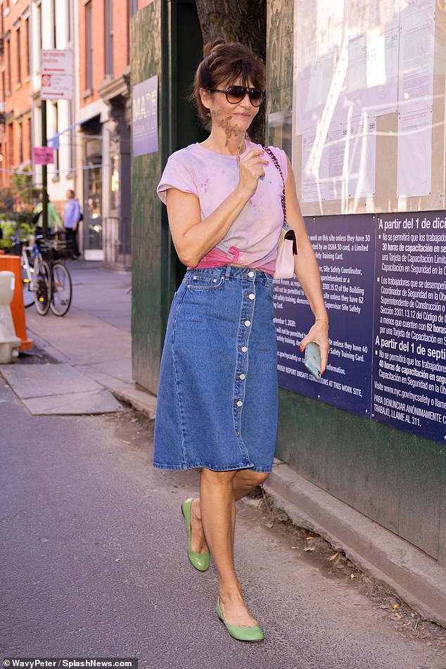 Casual: The Danish model paired her pink T-shirt with a button-up denim midi skirt and completed the outfit with double-bridge ombré sunglasses and sensible green flats