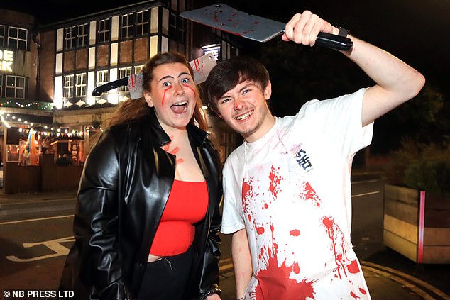 A man wearing a blood-stained T-shirt and an axe, while his partner wears a headband with an ax in the head