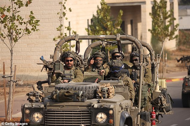 Israeli troops give a thumbs up to a photographer as they pass through the border town of Sderot, less than a kilometer from Gaza