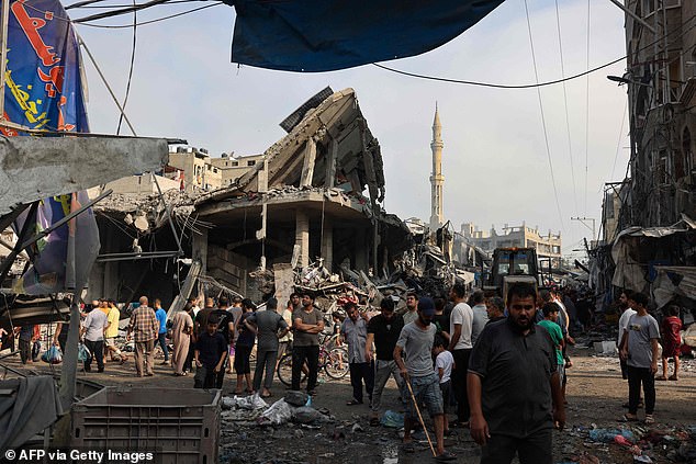 Palestinians examine destroyed buildings in Gaza City on Saturday.  The Israeli Army (IDF) is sending ground troops and armored vehicles to the occupied territory