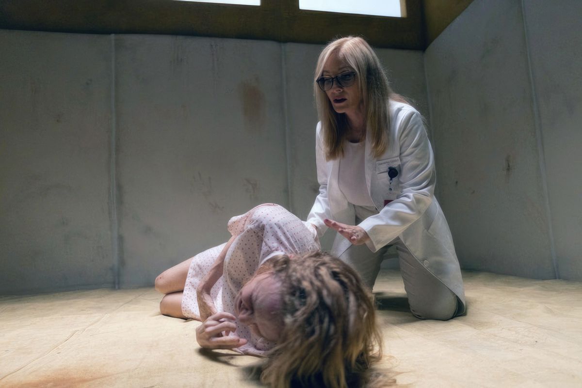 Elizabeth (Heather Graham, in a hospital gown), curls up crying on the floor of a naked psychiatric hospital cell as her psychiatrist friend (Barbara Crampton) kneels next to her and holds out a supportive hand to her in the flesh.