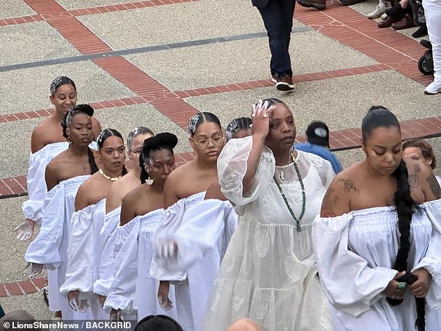 In her Saturday performance, Cullors went barefoot and wore an off-white ankle-length dress with gauze sleeves as she led the procession of women, as they were all tied together by long black braids of hair.